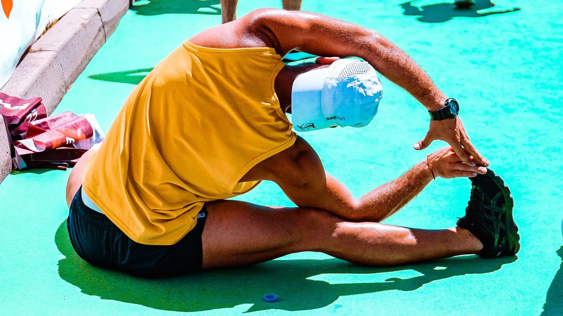 man wearing yellow tank top and black shorts stretching